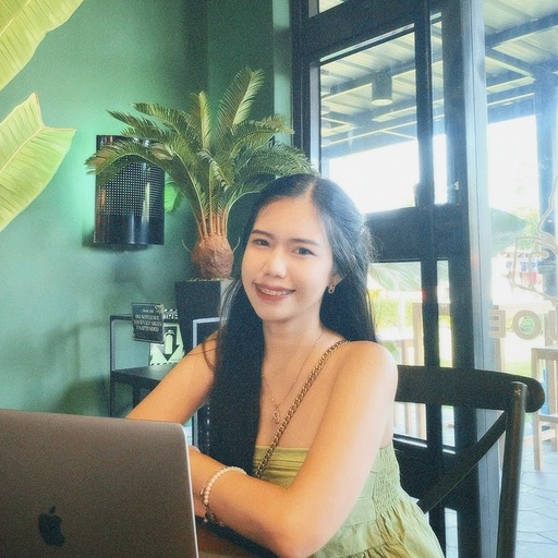 Smiling woman working on laptop in a café with plants.
